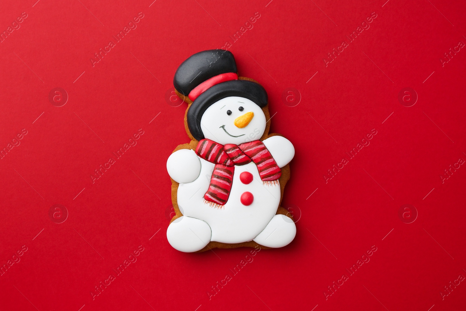 Photo of Tasty Christmas cookie in shape of snowman on red background, top view