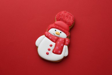 Photo of Tasty Christmas cookie in shape of snowman on red background, top view