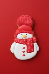 Photo of Tasty Christmas cookie in shape of snowman on red background, top view