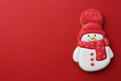 Photo of Tasty Christmas cookie in shape of snowman on red background, top view. Space for text