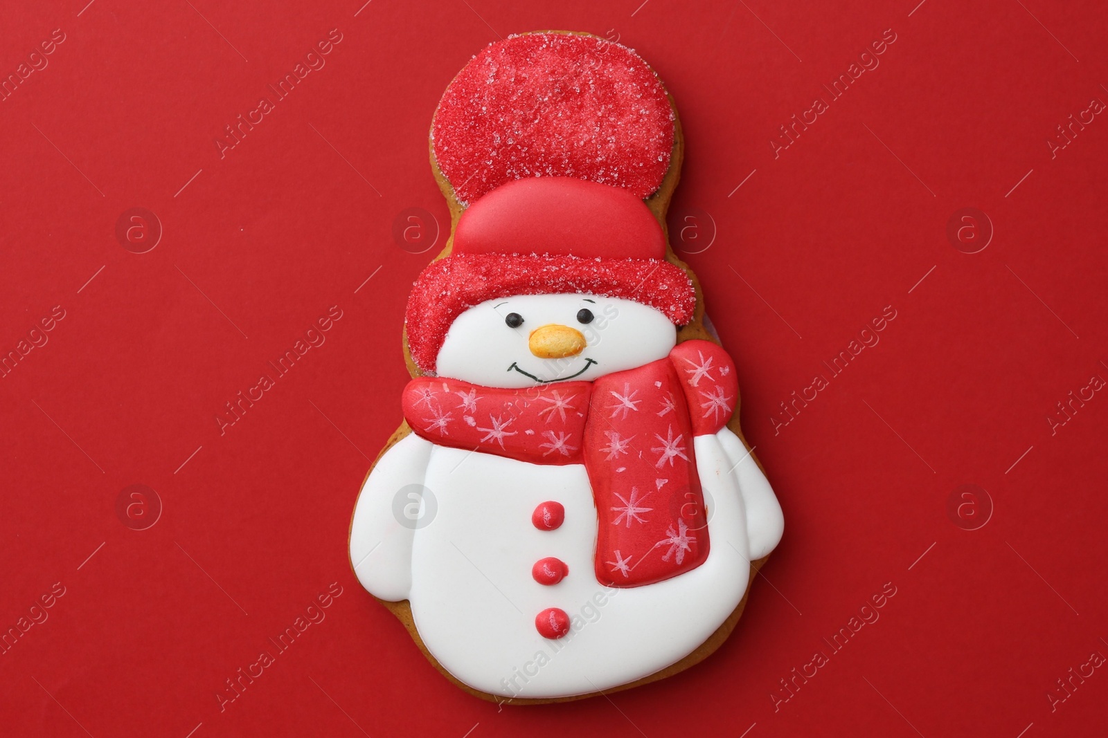 Photo of Tasty Christmas cookie in shape of snowman on red background, top view