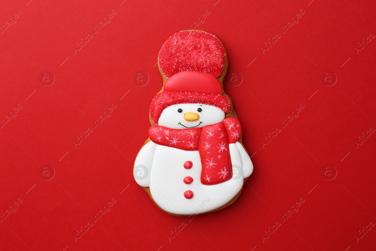 Photo of Tasty Christmas cookie in shape of snowman on red background, top view