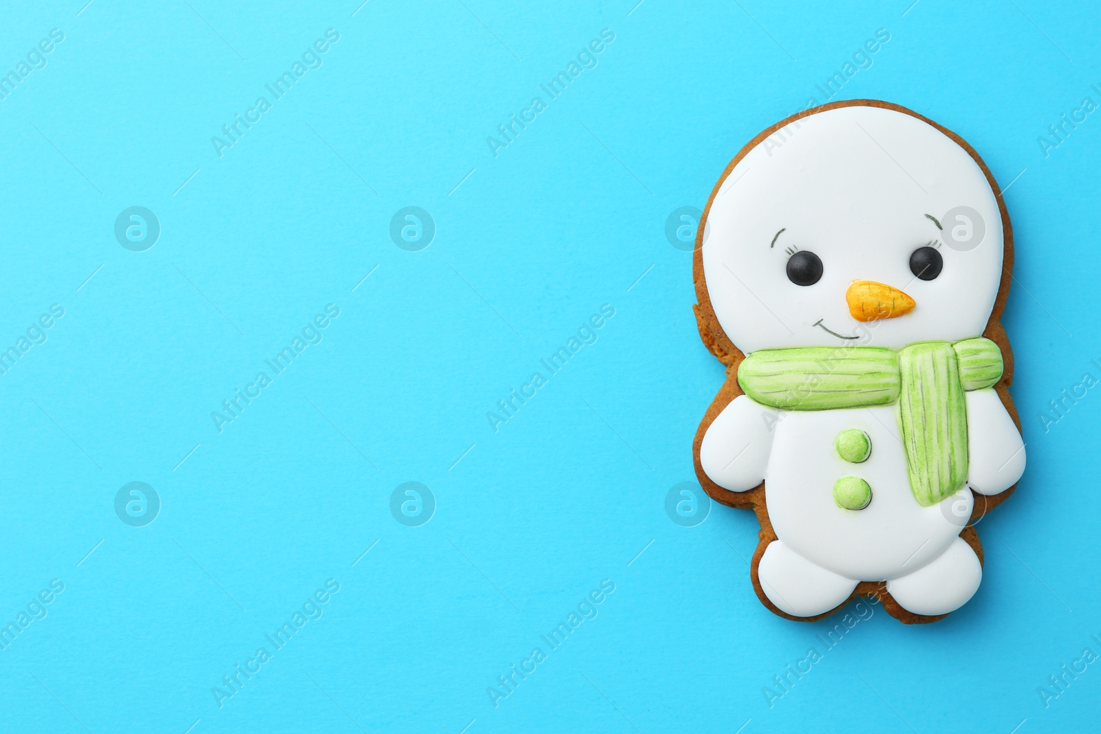 Photo of Tasty Christmas cookie in shape of snowman on light blue background, top view. Space for text