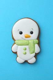 Photo of Tasty Christmas cookie in shape of snowman on light blue background, top view