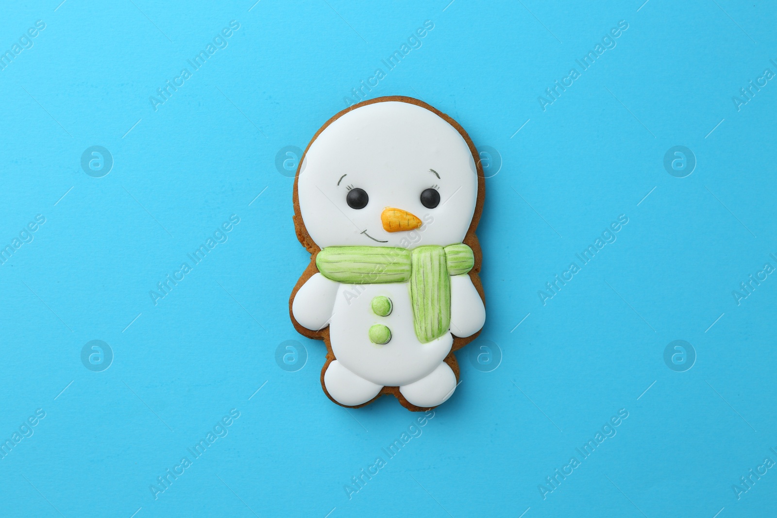 Photo of Tasty Christmas cookie in shape of snowman on light blue background, top view