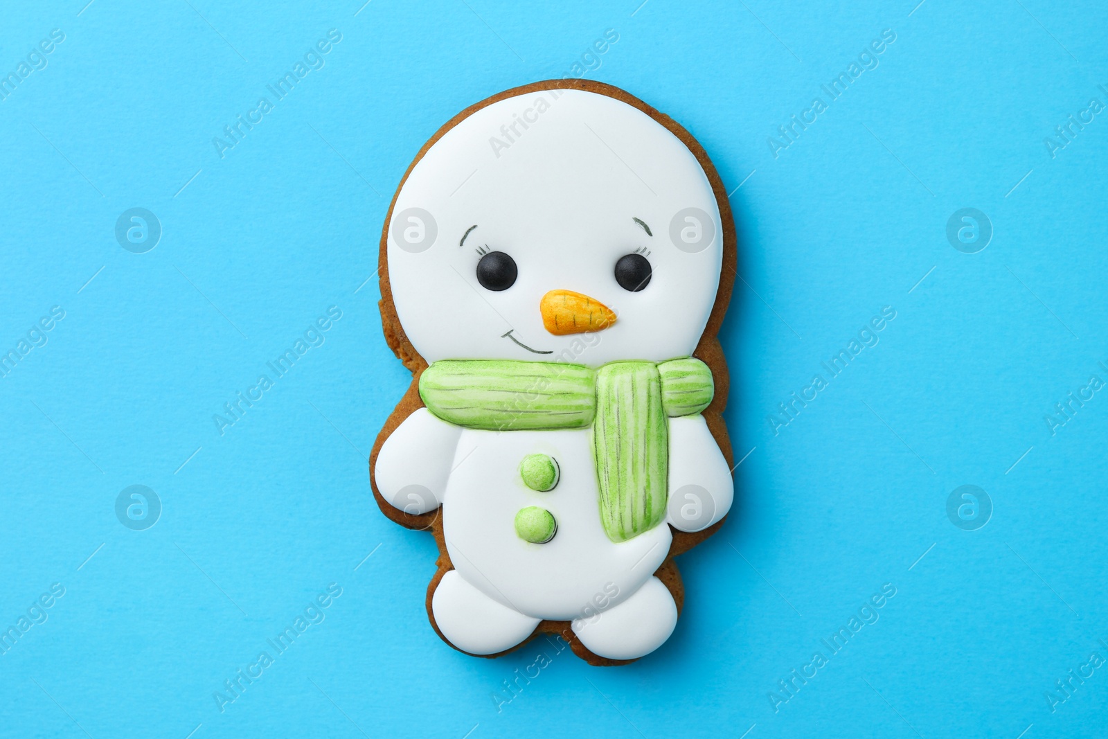 Photo of Tasty Christmas cookie in shape of snowman on light blue background, top view