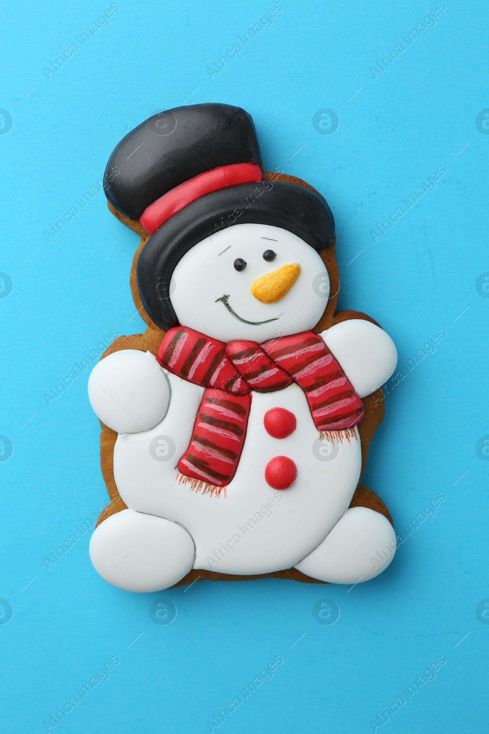 Photo of Tasty Christmas cookie in shape of snowman on light blue background, top view