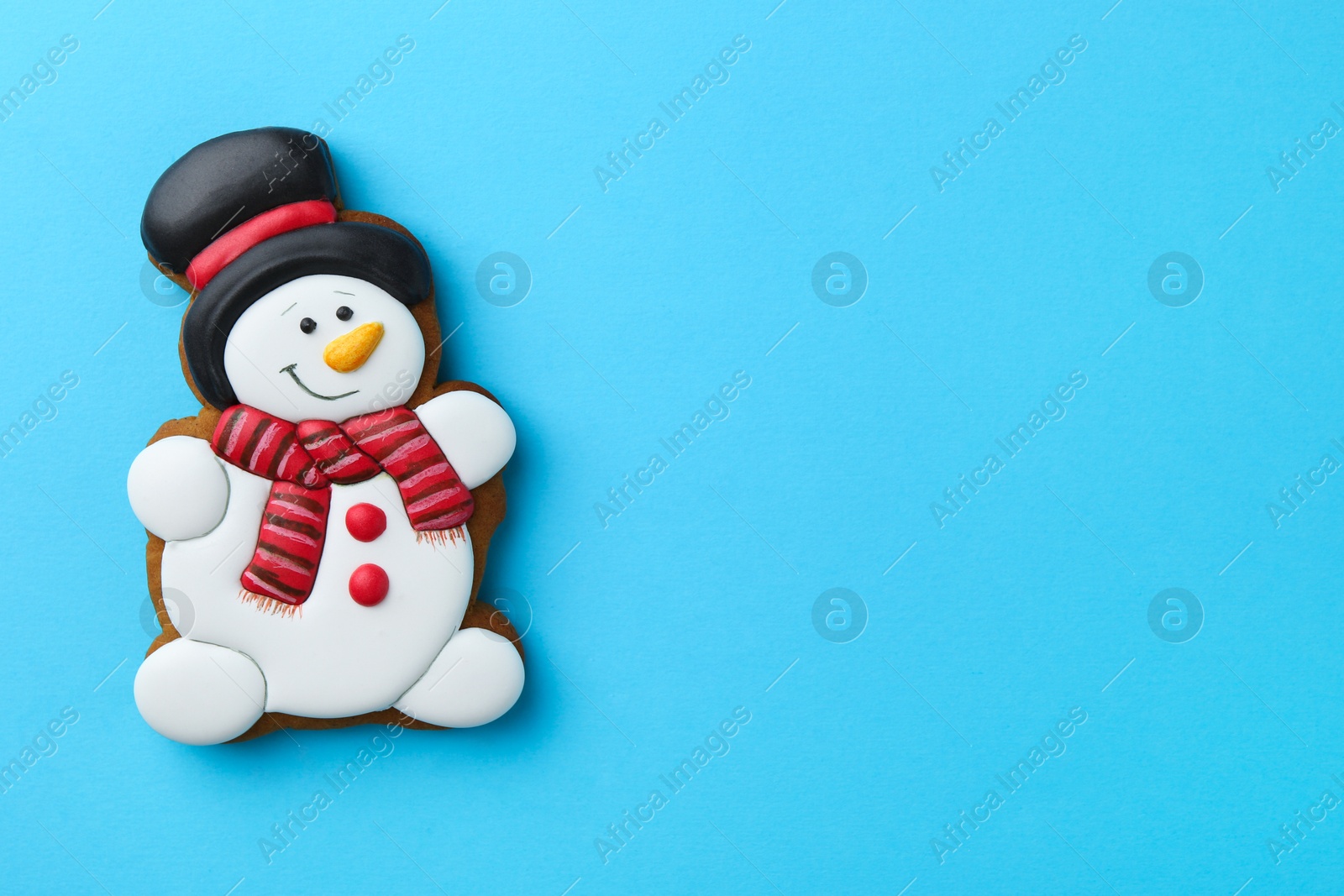 Photo of Tasty Christmas cookie in shape of snowman on light blue background, top view. Space for text