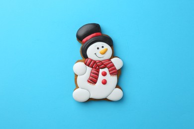 Photo of Tasty Christmas cookie in shape of snowman on light blue background, top view