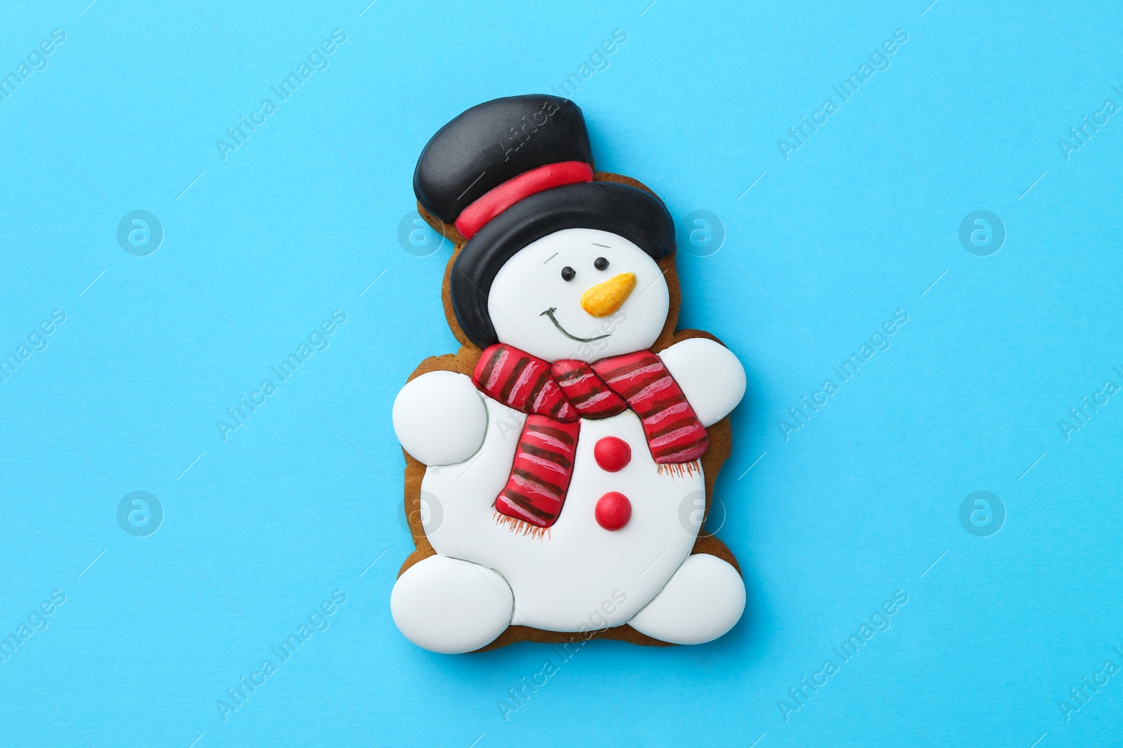 Photo of Tasty Christmas cookie in shape of snowman on light blue background, top view