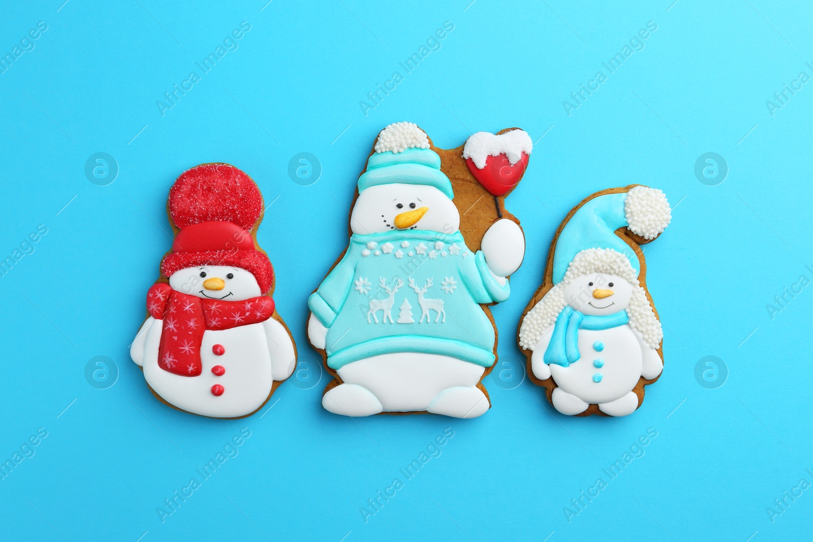 Photo of Tasty Christmas cookies in shape of snowman on light blue background, flat lay