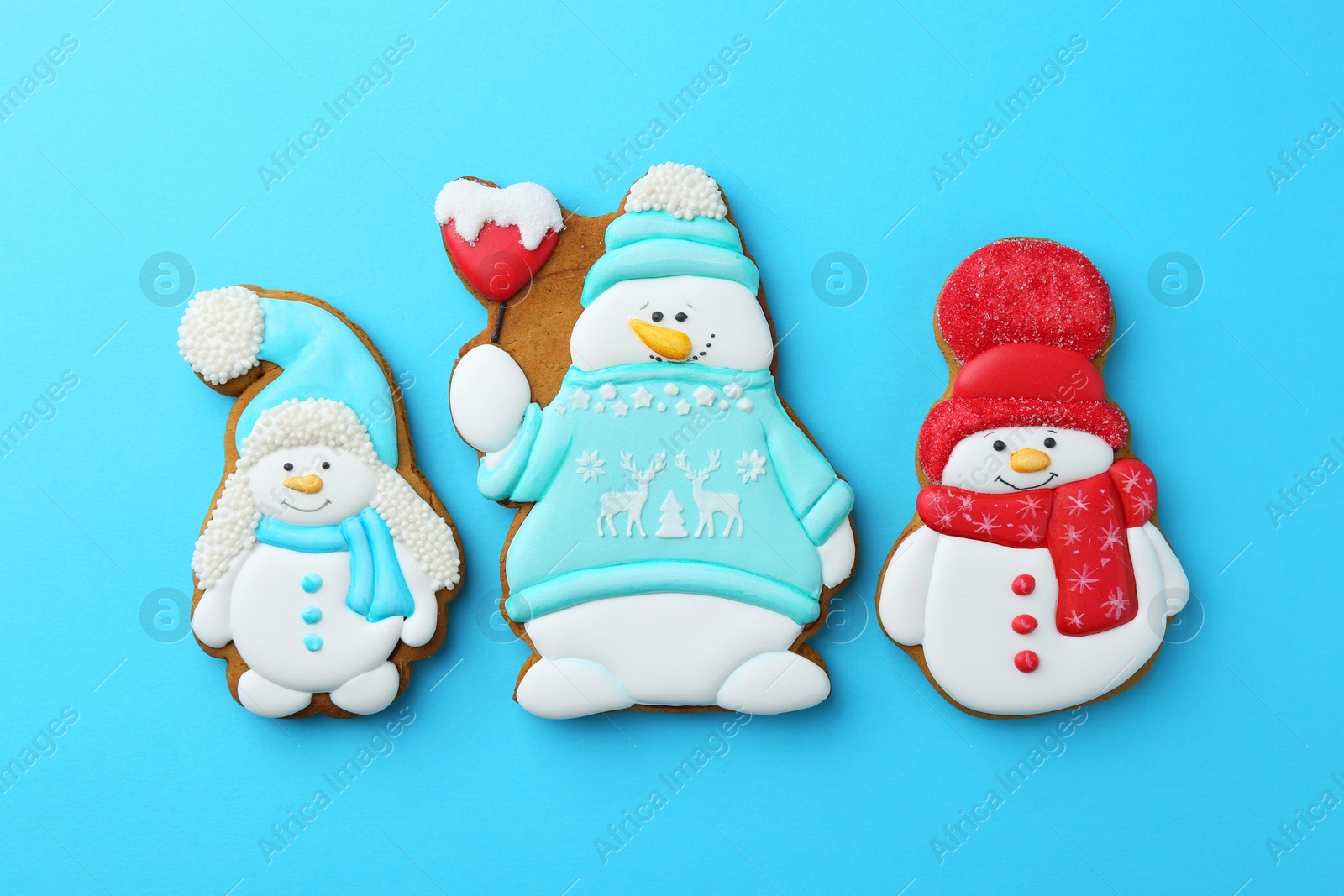 Photo of Tasty Christmas cookies in shape of snowman on light blue background, flat lay