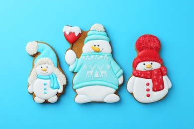 Photo of Tasty Christmas cookies in shape of snowman on light blue background, flat lay