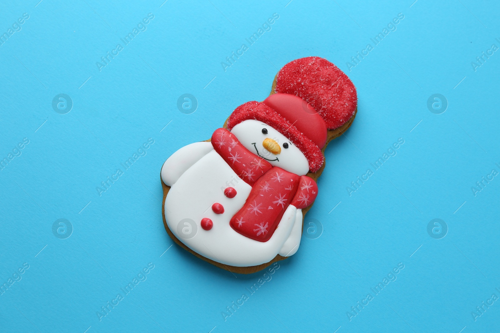 Photo of Tasty Christmas cookie in shape of snowman on light blue background, top view