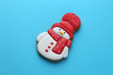 Photo of Tasty Christmas cookie in shape of snowman on light blue background, top view