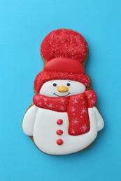 Photo of Tasty Christmas cookie in shape of snowman on light blue background, top view