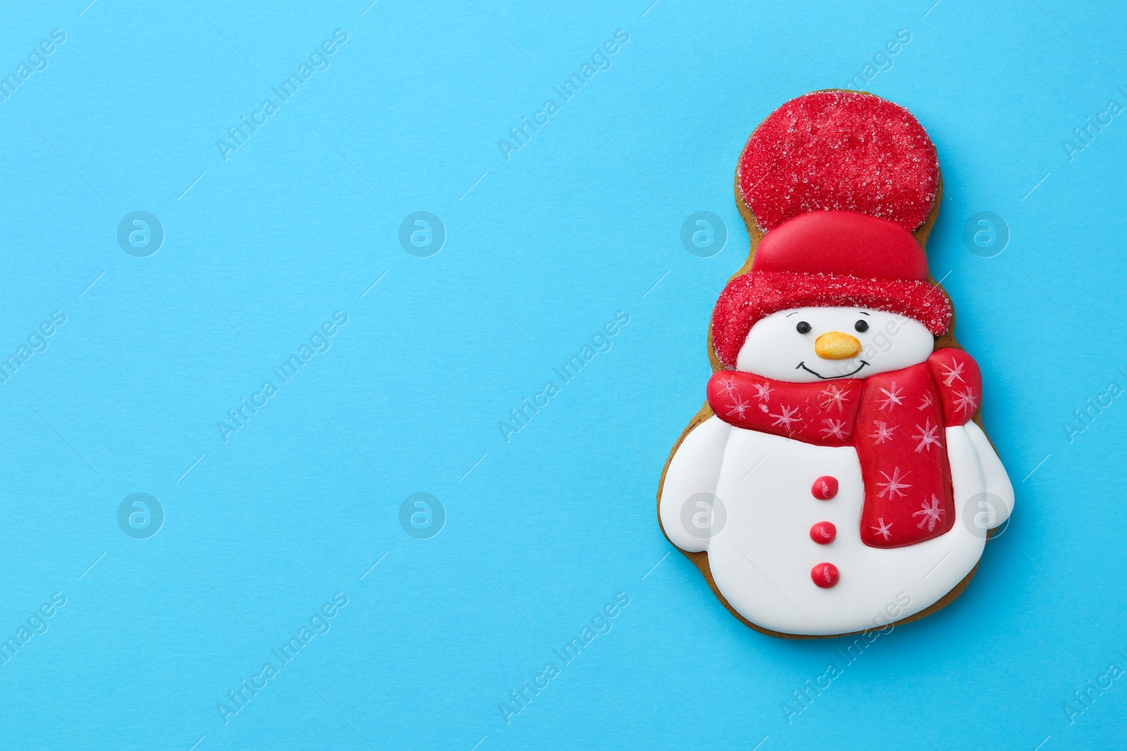 Photo of Tasty Christmas cookie in shape of snowman on light blue background, top view. Space for text