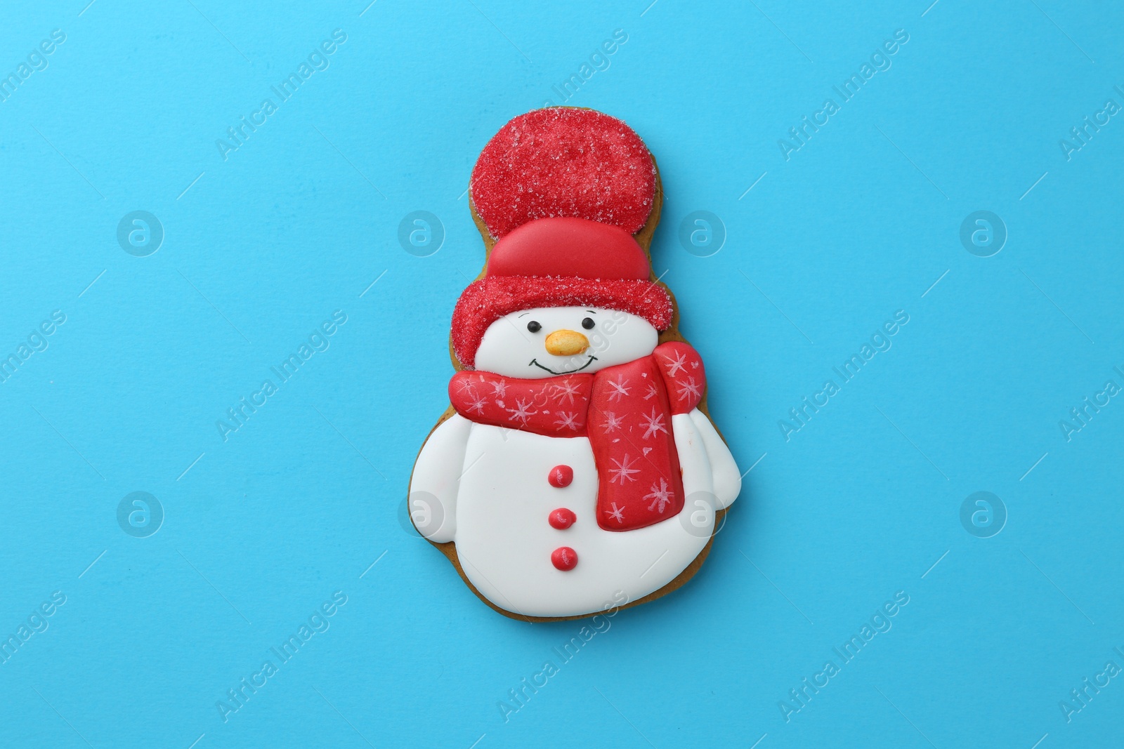 Photo of Tasty Christmas cookie in shape of snowman on light blue background, top view