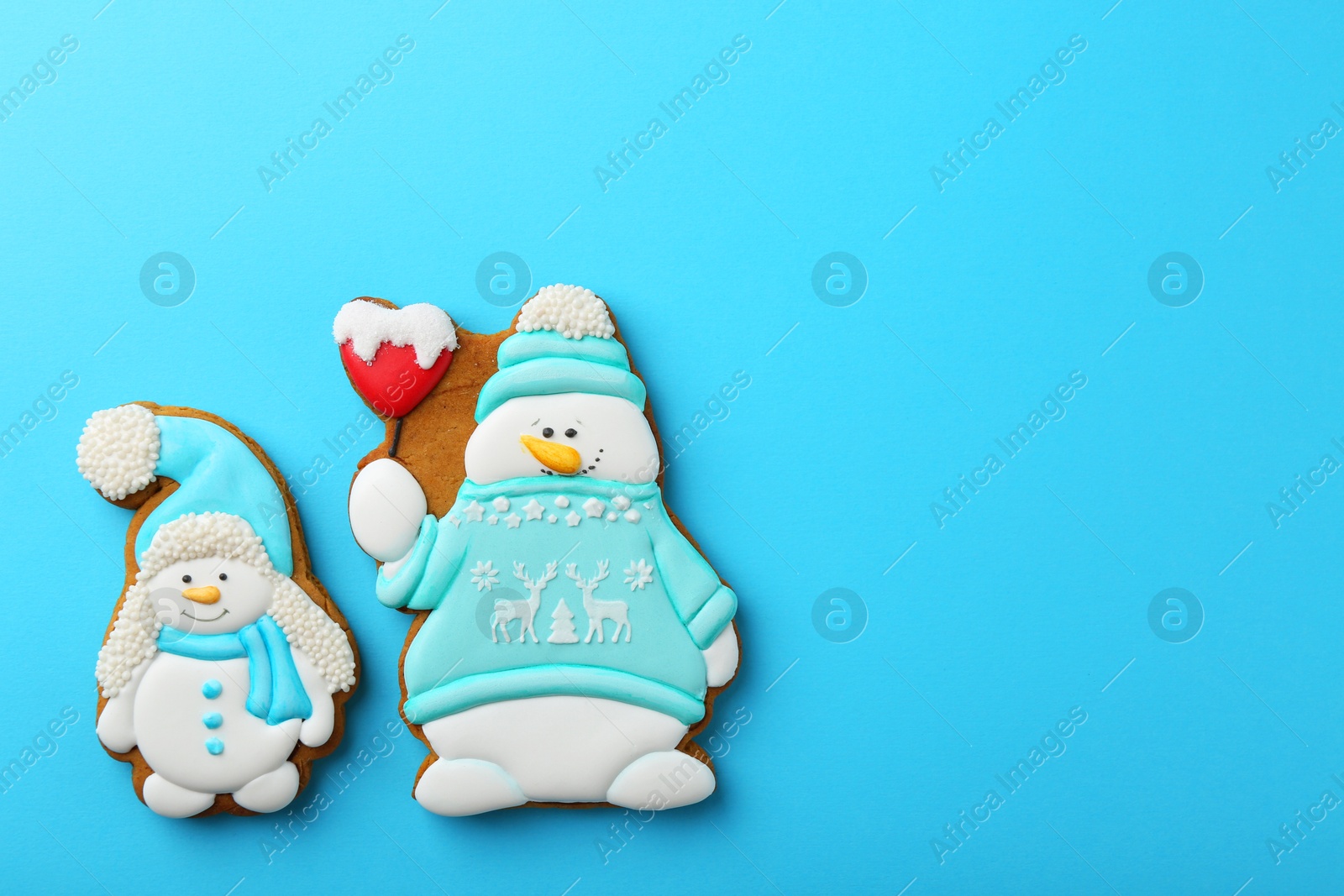 Photo of Tasty Christmas cookies in shape of snowman on light blue background, flat lay. Space for text