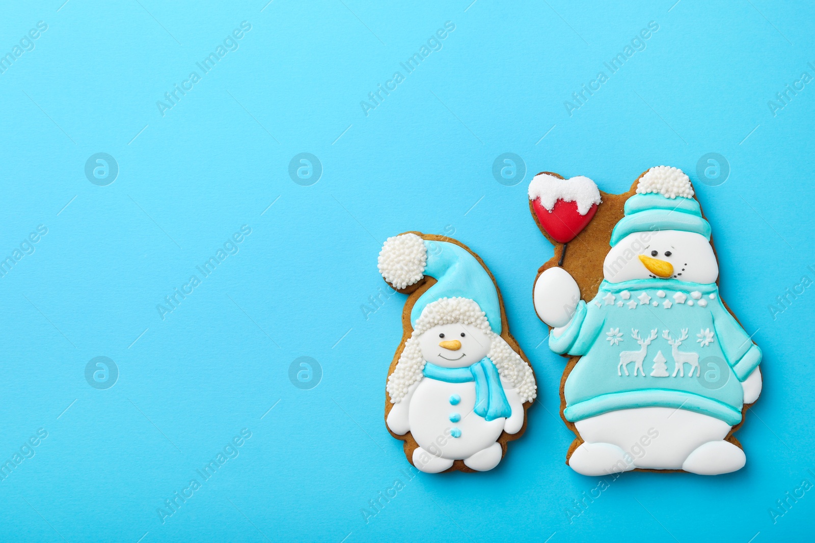 Photo of Tasty Christmas cookies in shape of snowman on light blue background, flat lay. Space for text