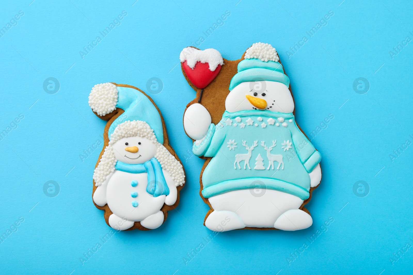 Photo of Tasty Christmas cookies in shape of snowman on light blue background, flat lay