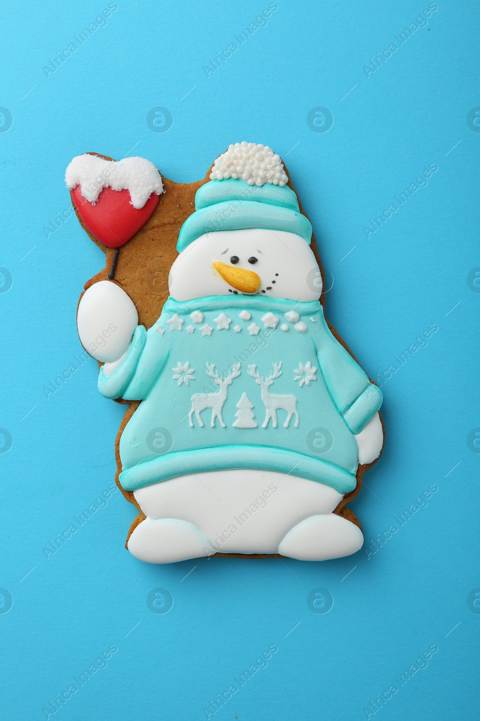 Photo of Tasty Christmas cookie in shape of snowman on light blue background, top view