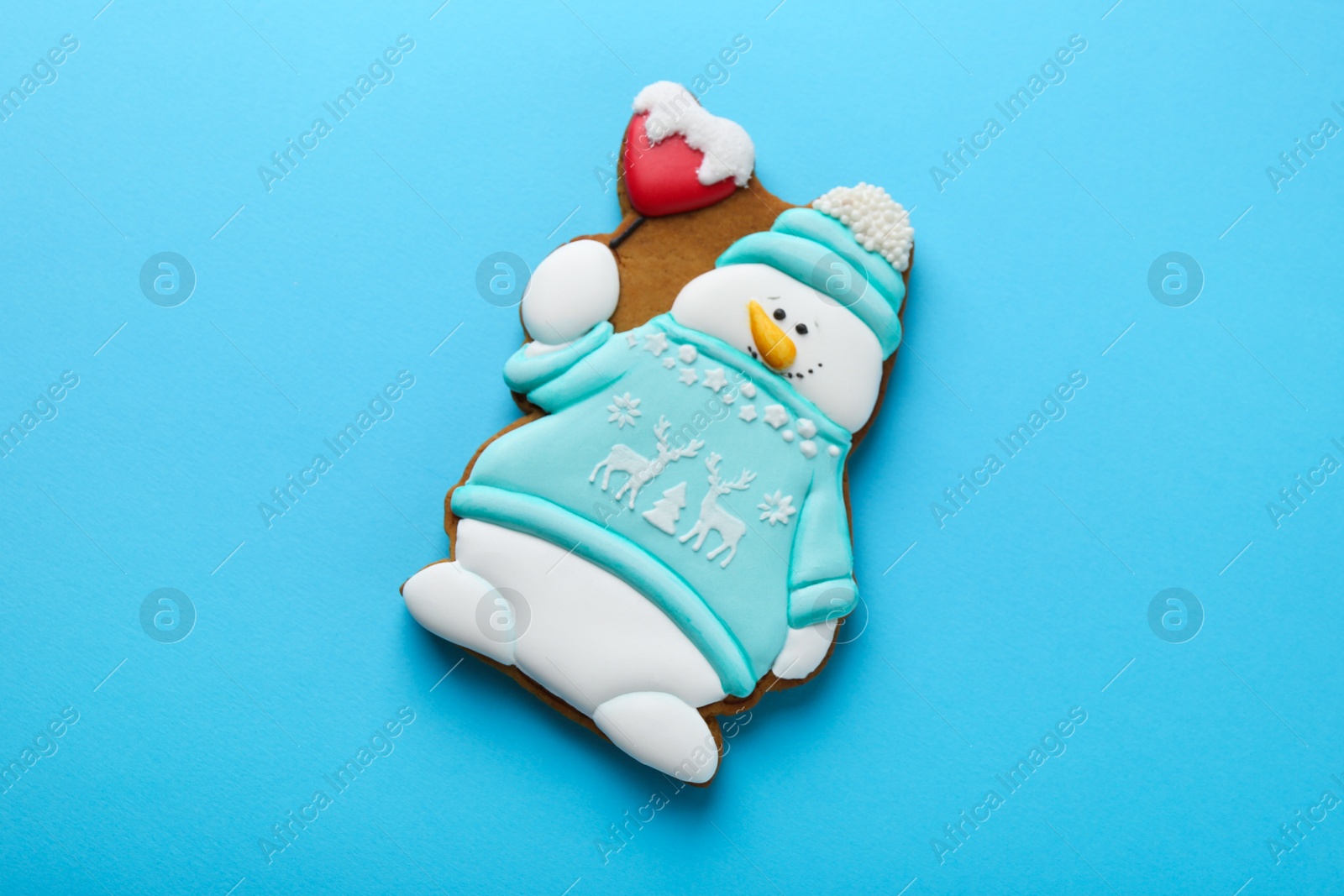 Photo of Tasty Christmas cookie in shape of snowman on light blue background, top view