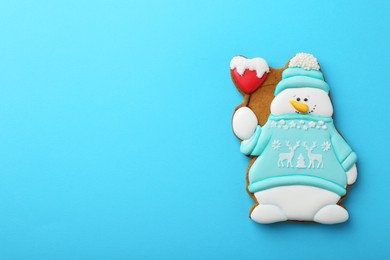 Tasty Christmas cookie in shape of snowman on light blue background, top view. Space for text