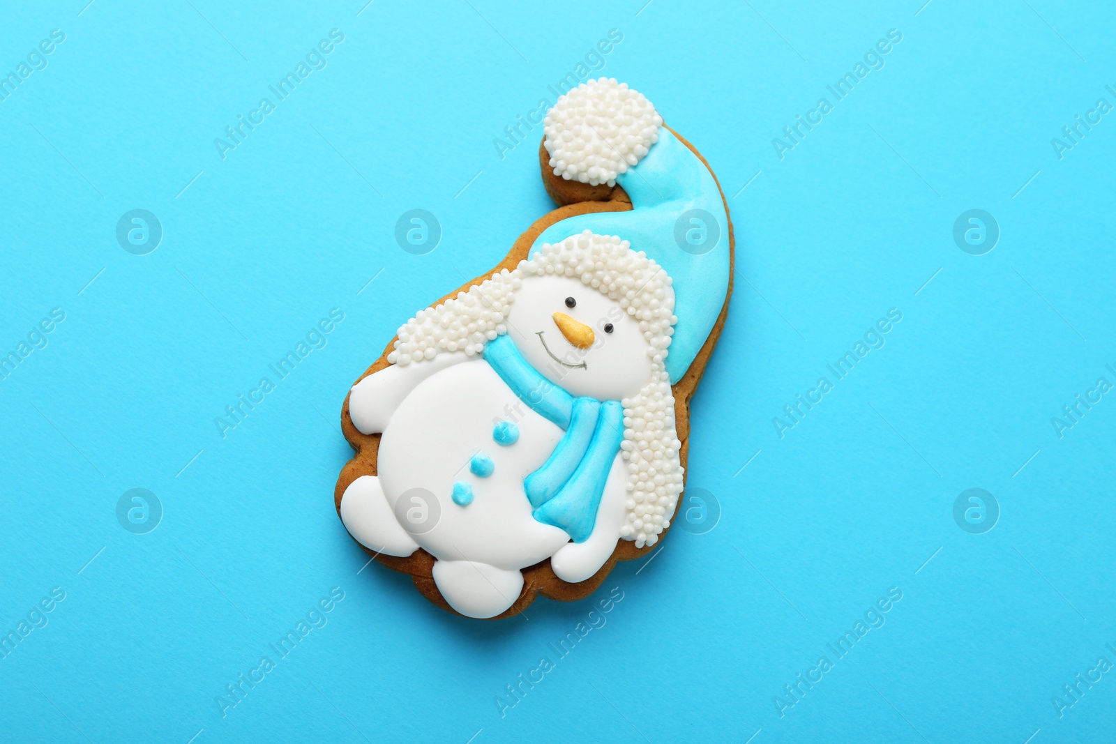 Photo of Tasty Christmas cookie in shape of snowman on light blue background, top view