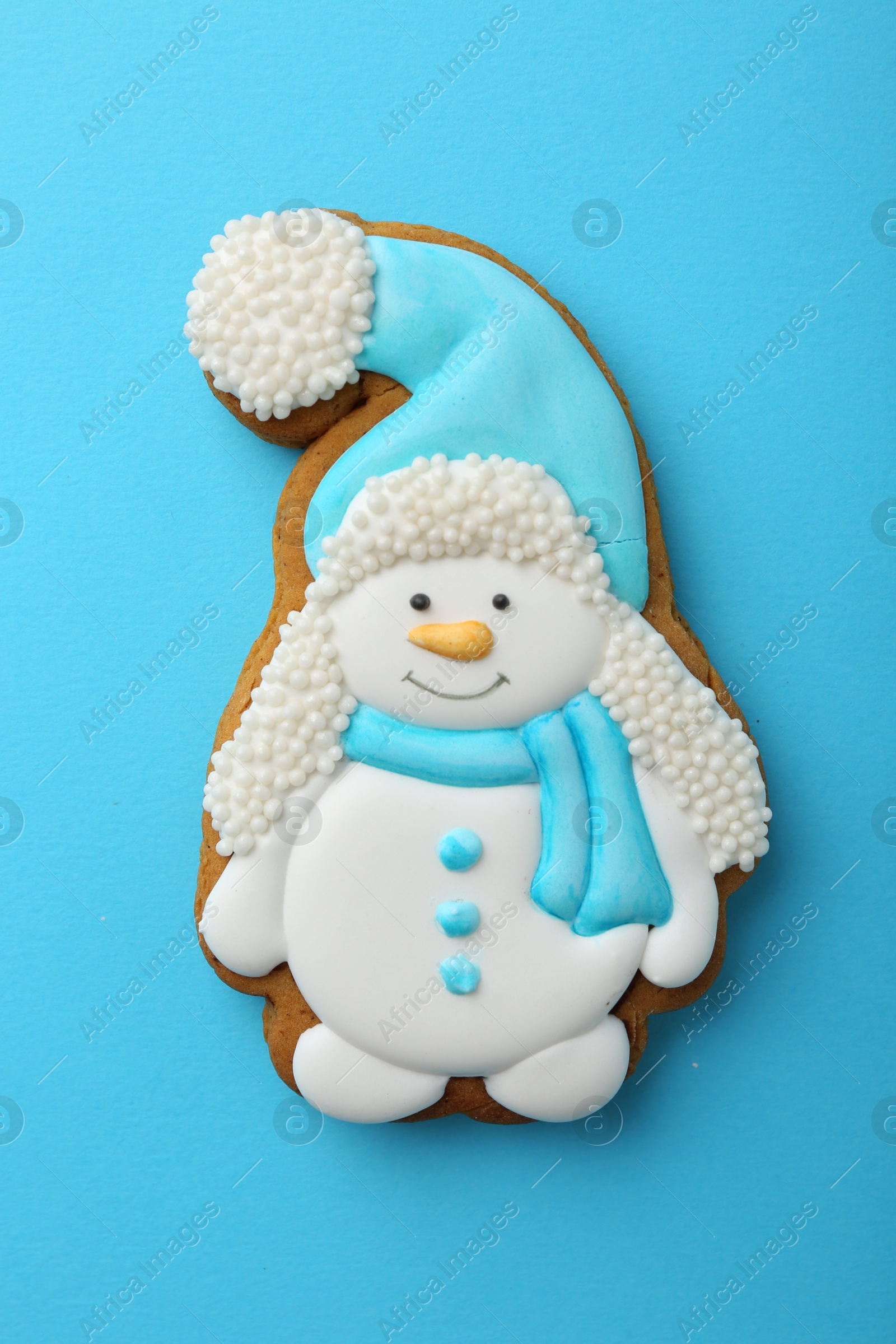 Photo of Tasty Christmas cookie in shape of snowman on light blue background, top view