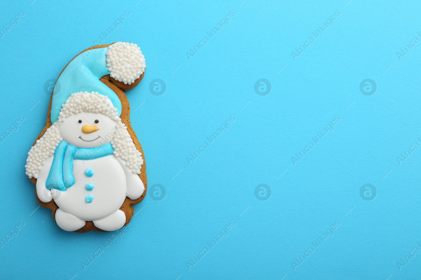 Photo of Tasty Christmas cookie in shape of snowman on light blue background, top view. Space for text