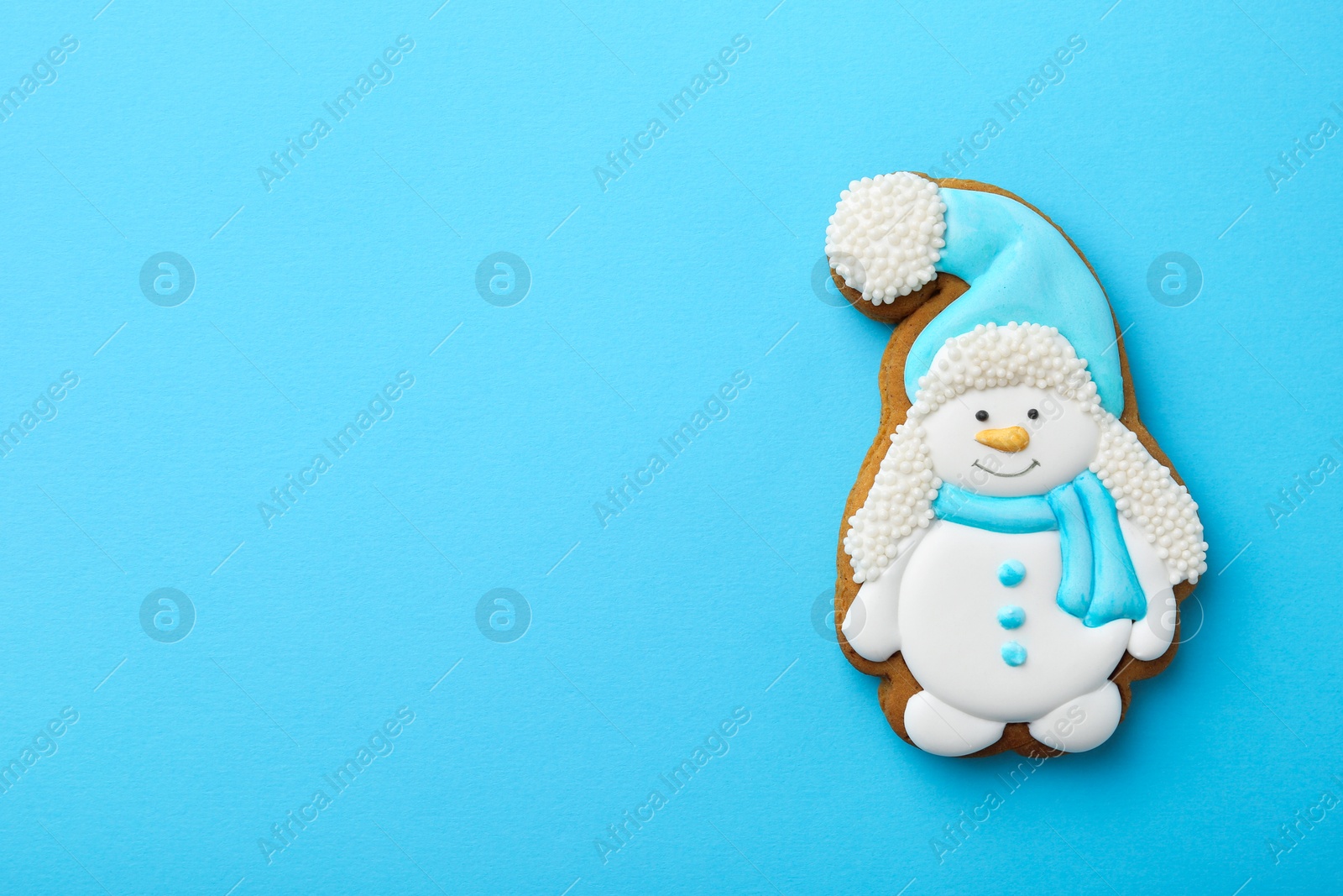 Photo of Tasty Christmas cookie in shape of snowman on light blue background, top view. Space for text