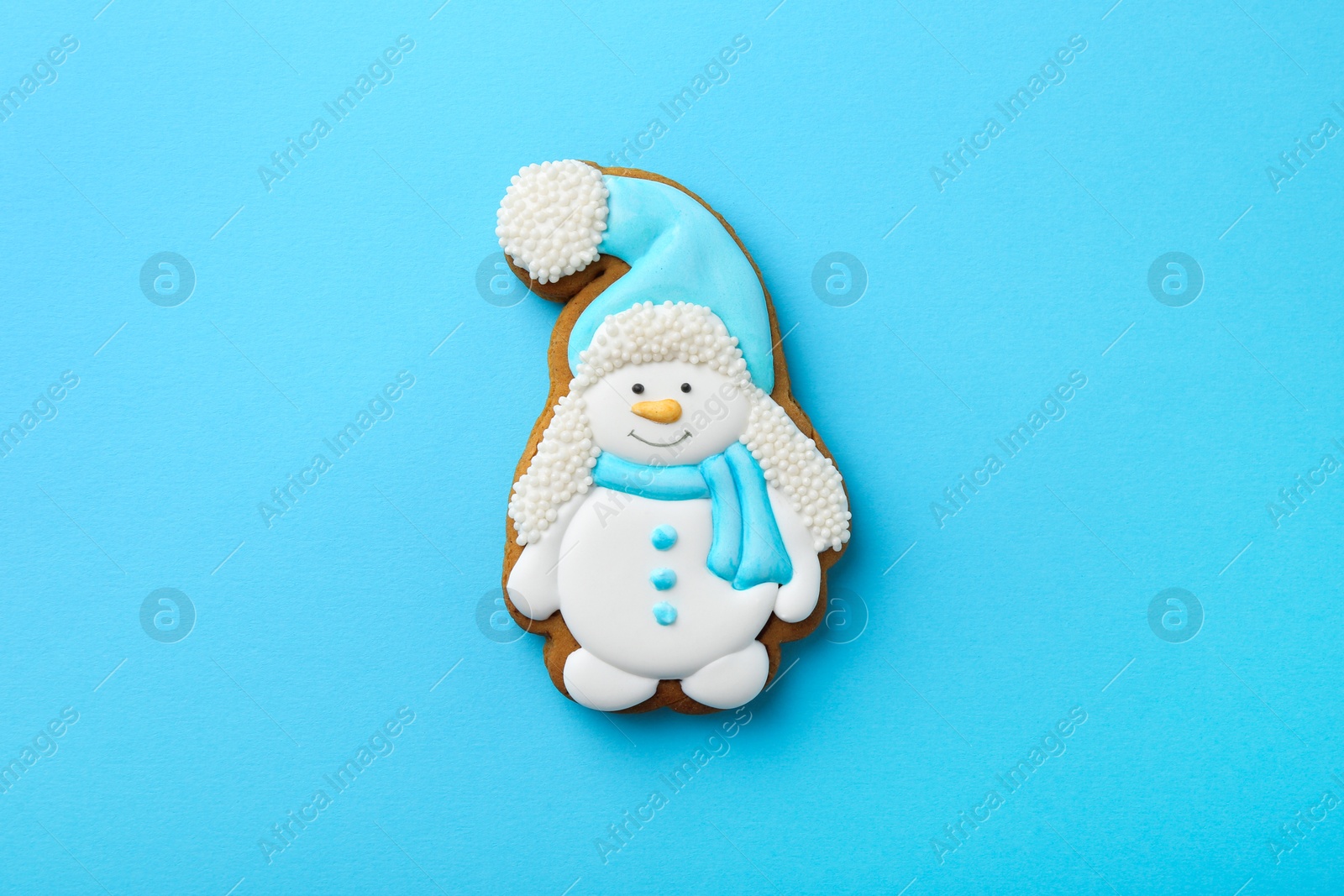 Photo of Tasty Christmas cookie in shape of snowman on light blue background, top view