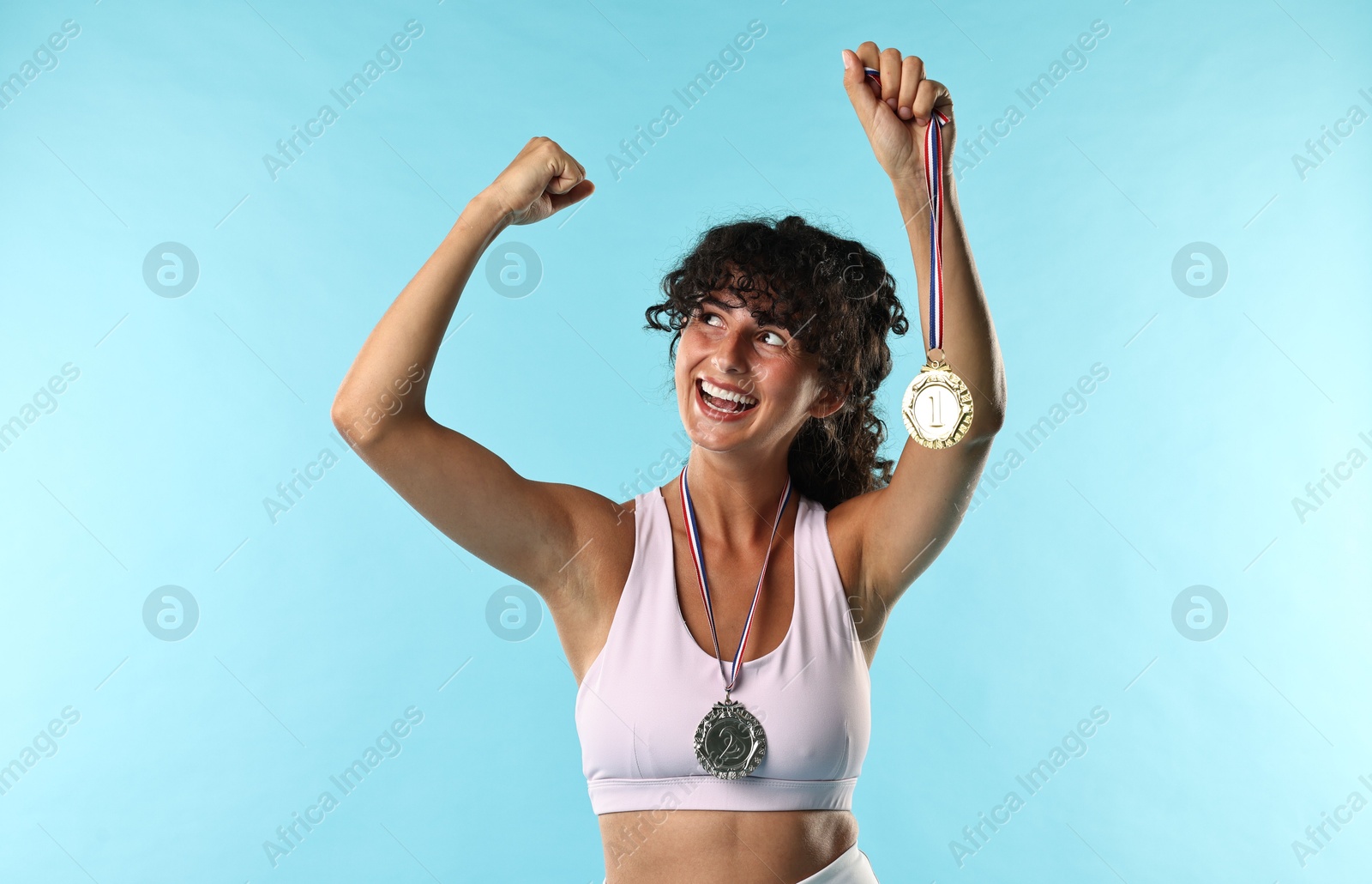 Photo of Happy winner with different medals on light blue background