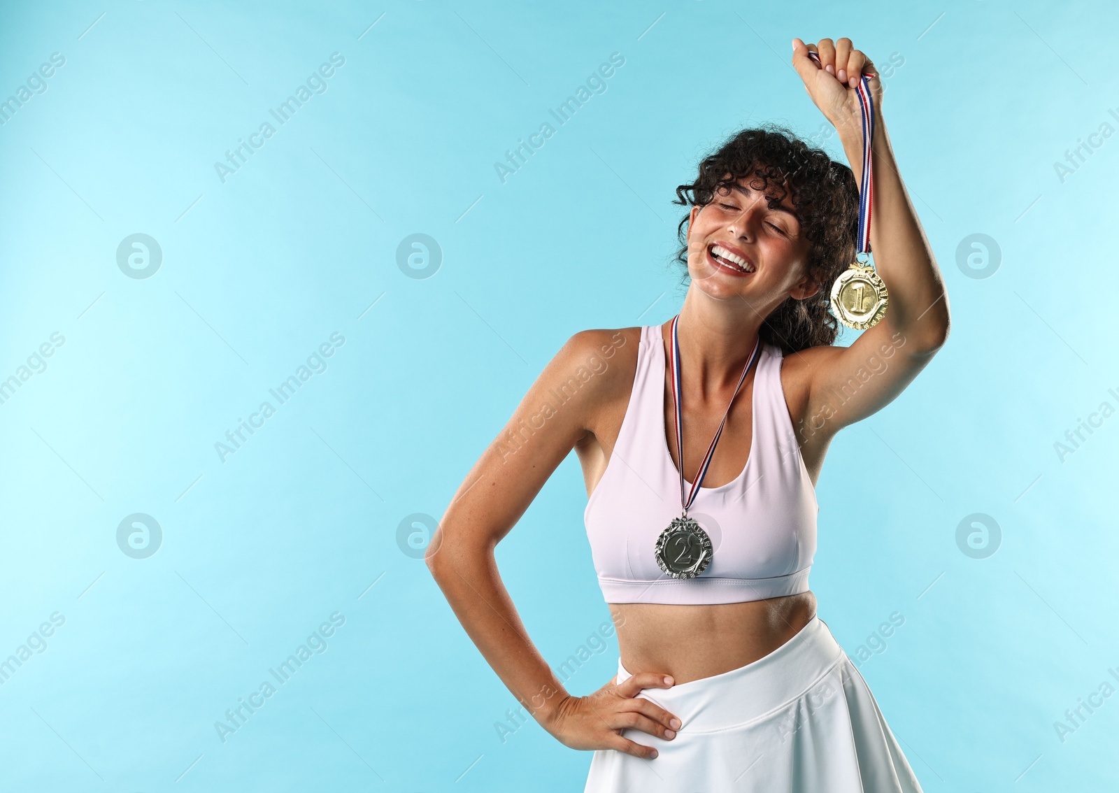 Photo of Happy winner with different medals on light blue background. Space for text