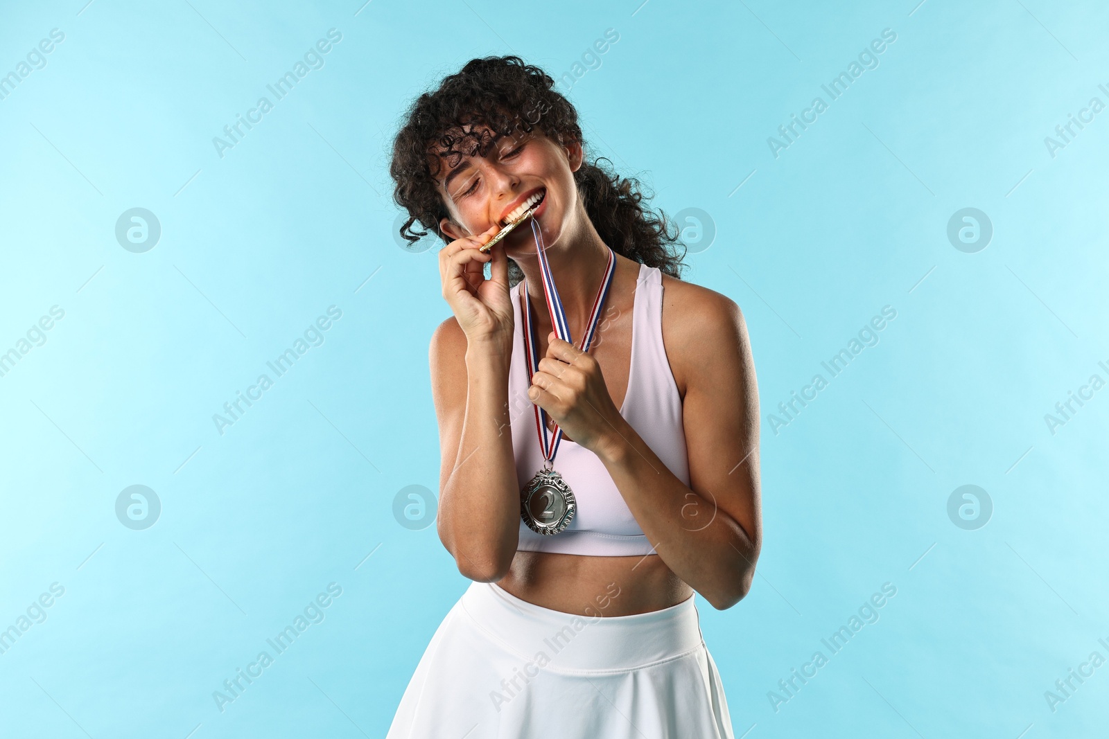 Photo of Happy winner with different medals on light blue background