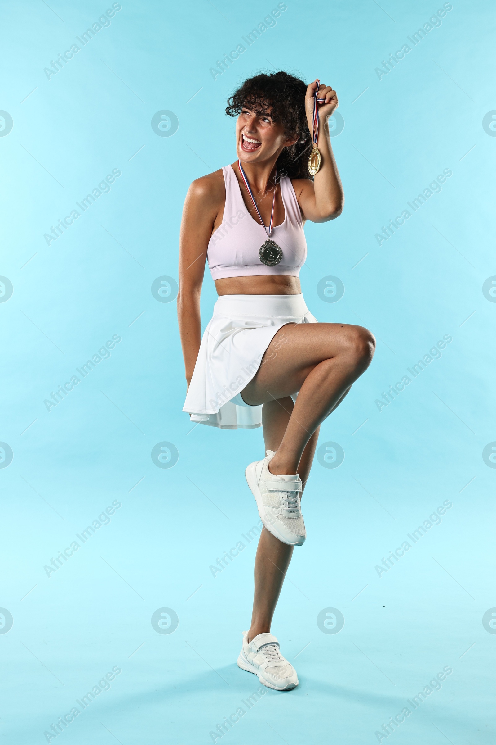 Photo of Happy winner with different medals on light blue background