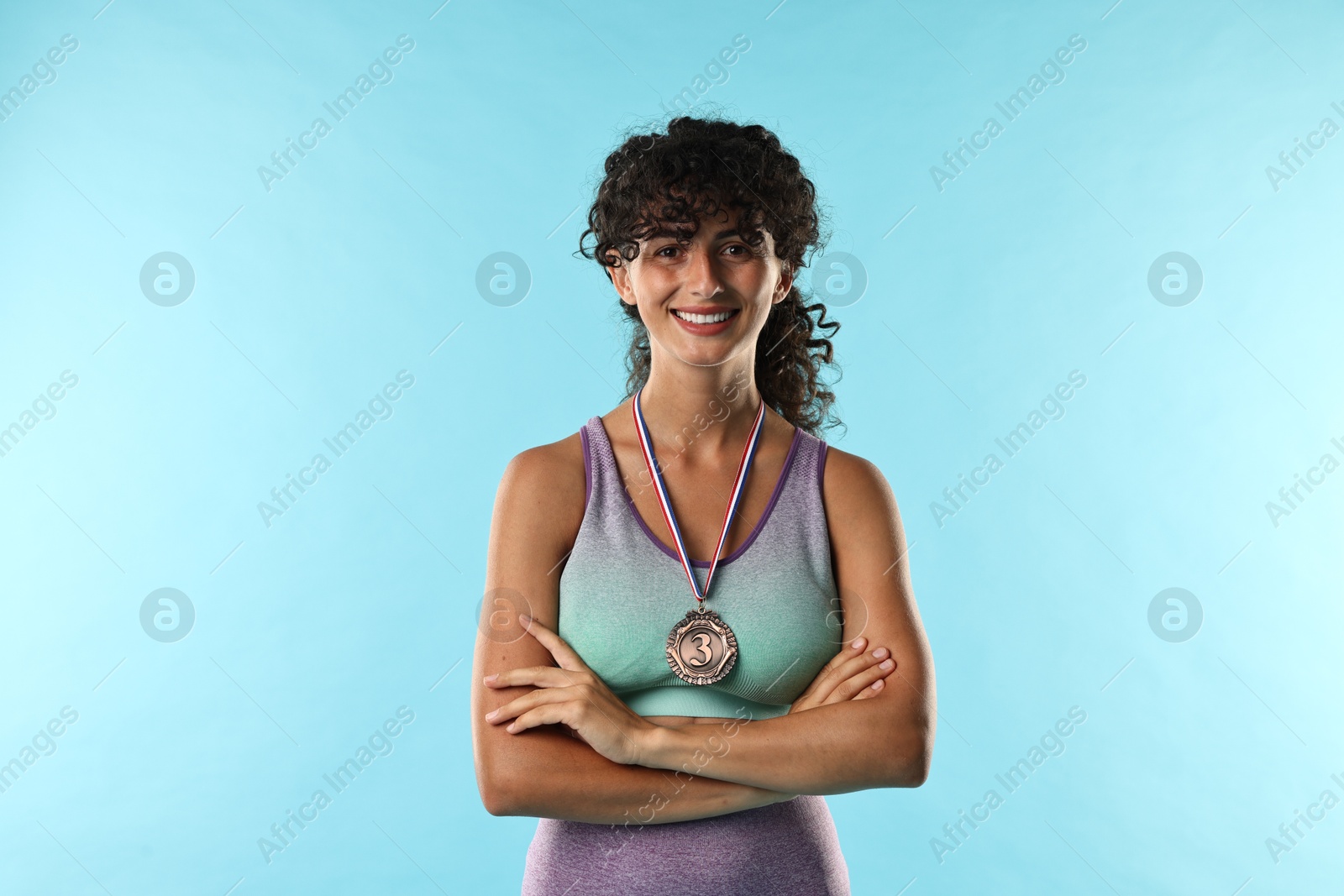 Photo of Happy winner with bronze medal on light blue background