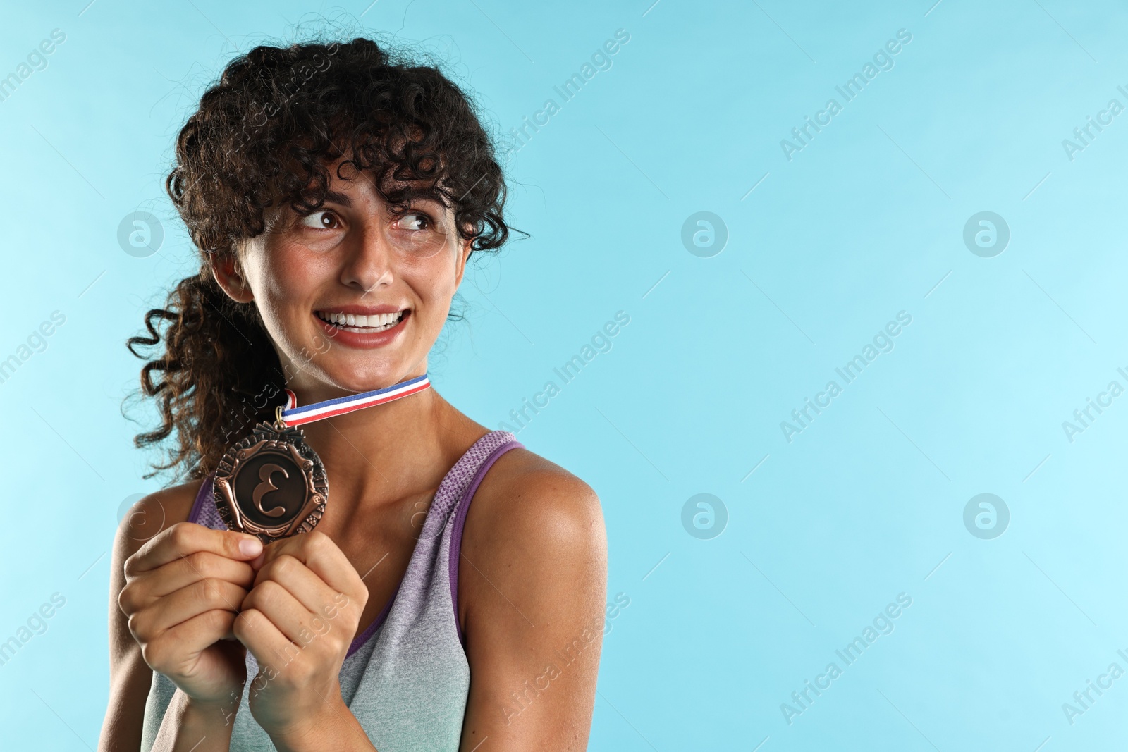 Photo of Happy winner with bronze medal on light blue background. Space for text