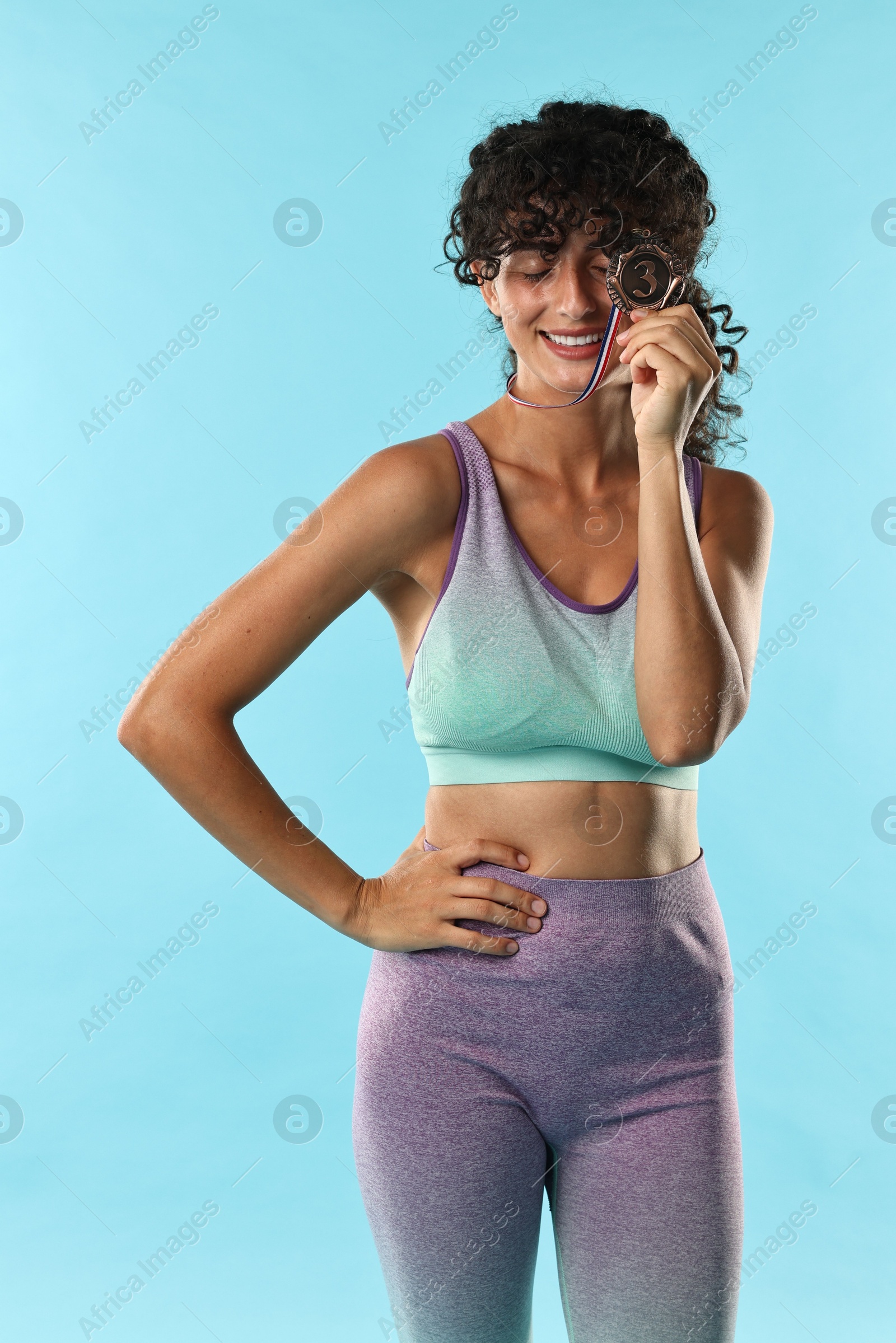 Photo of Happy winner with bronze medal on light blue background