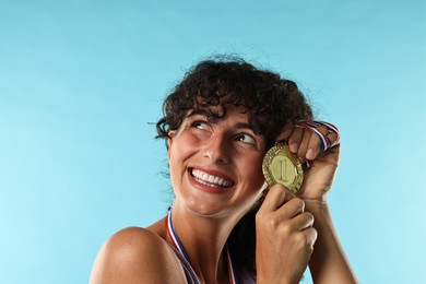 Photo of Happy winner with golden medal on light blue background, closeup