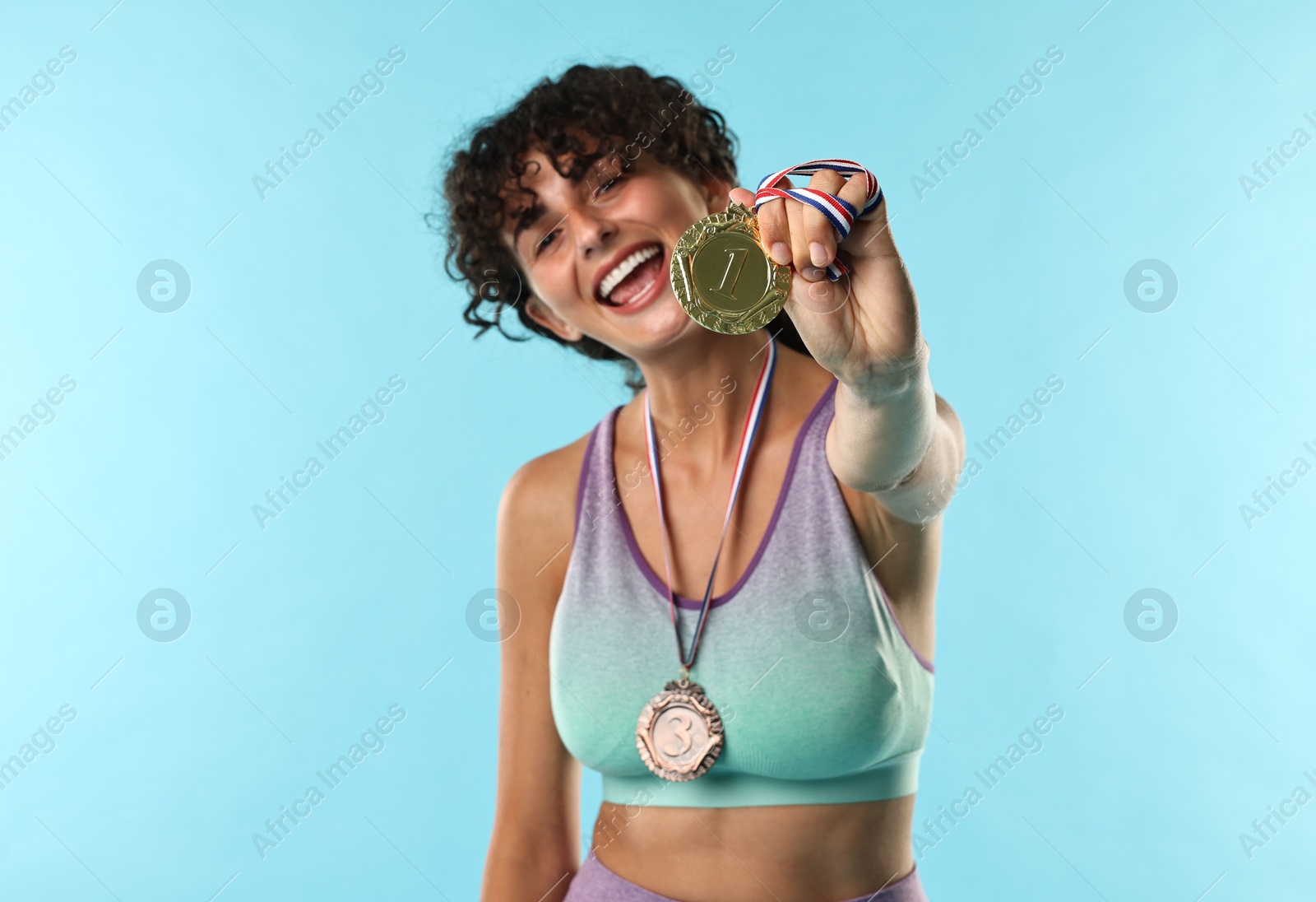 Photo of Happy winner with different medals on light blue background