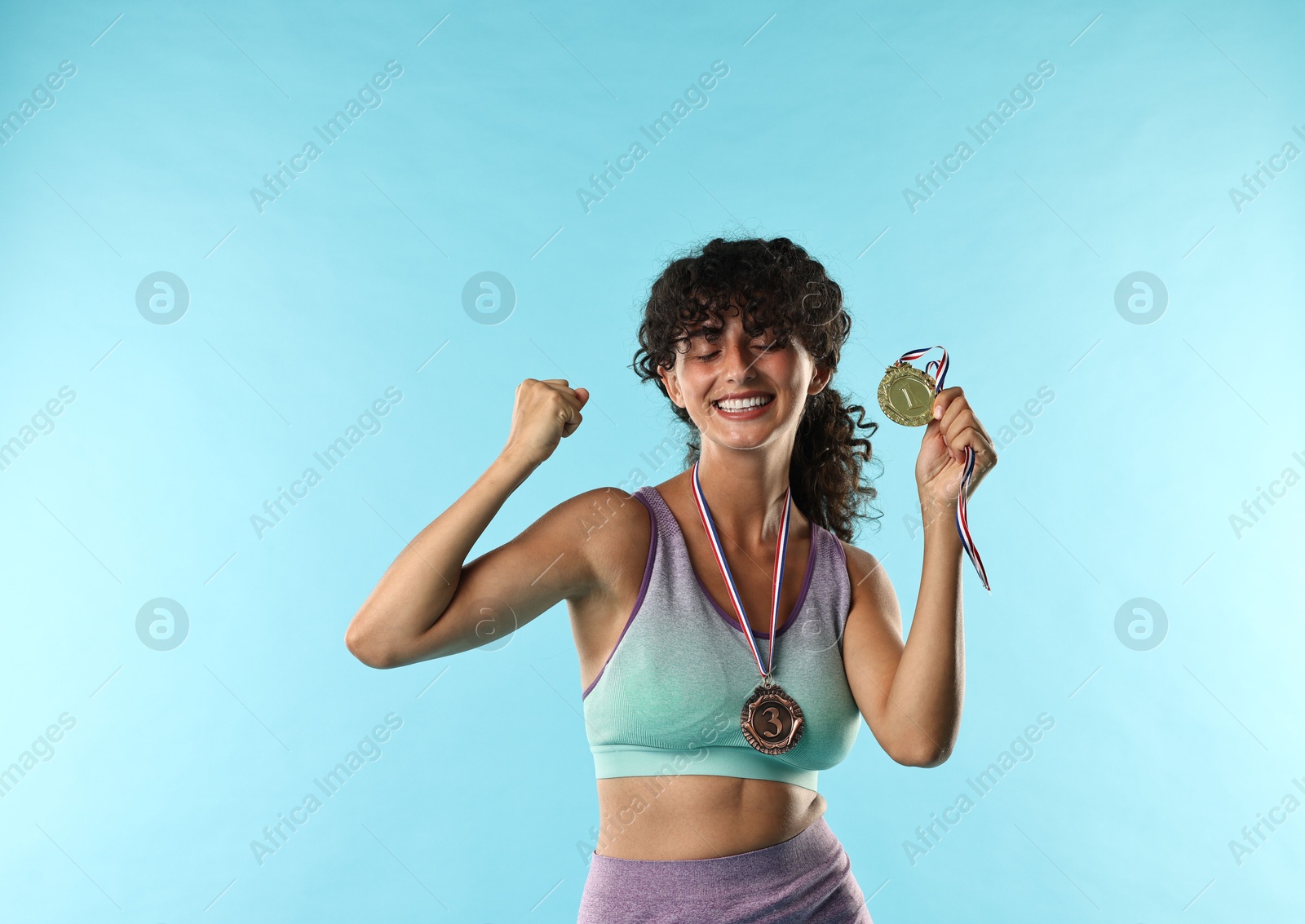 Photo of Happy winner with different medals on light blue background