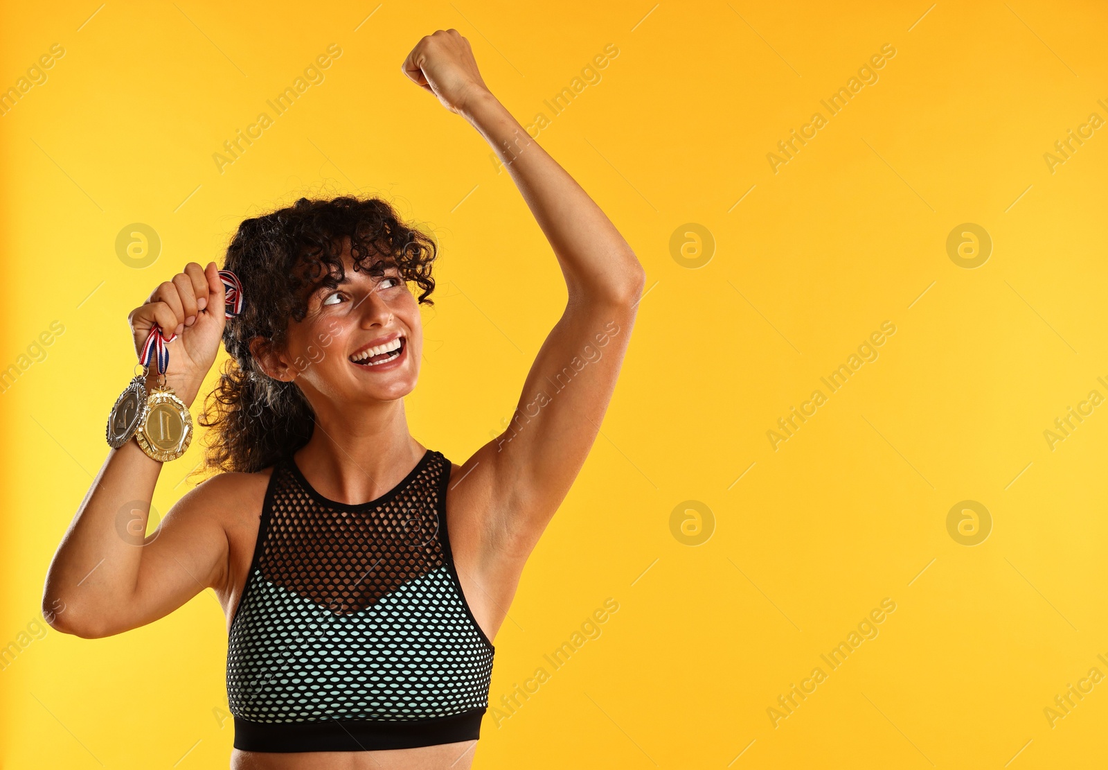 Photo of Happy winner with different medals on yellow background. Space for text