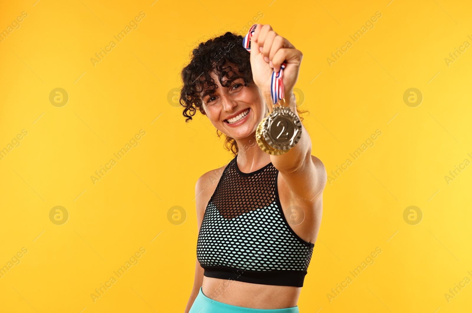 Photo of Happy winner showing different medals on yellow background