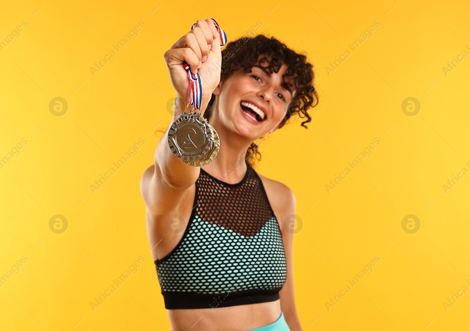 Photo of Happy winner showing different medals on yellow background