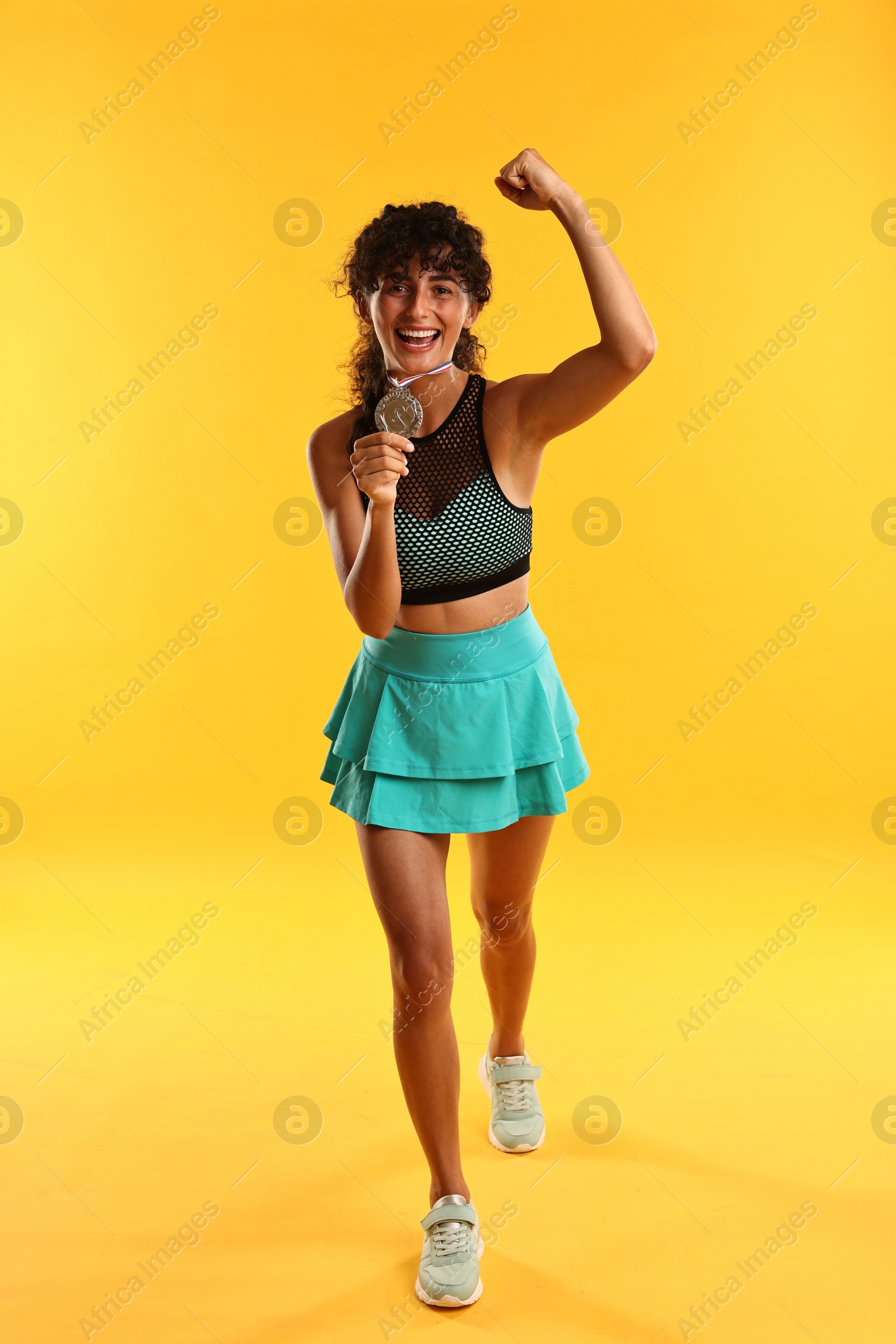 Photo of Happy winner with silver medal showing muscles on yellow background