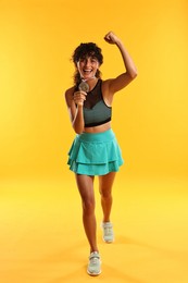 Happy winner with silver medal showing muscles on yellow background