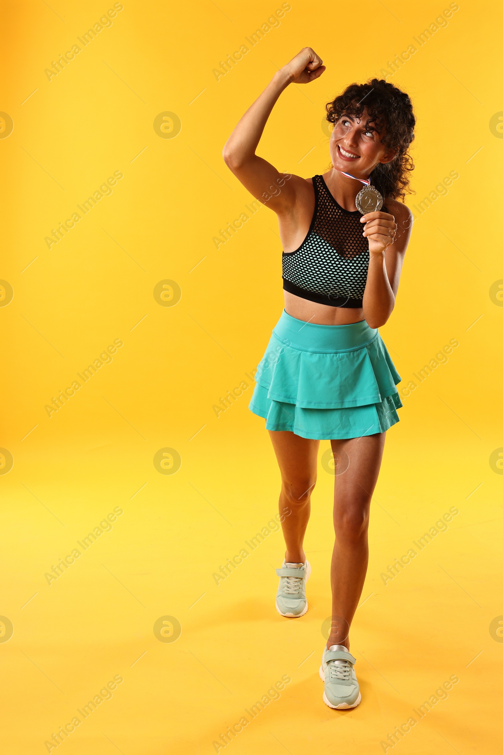 Photo of Winner with silver medal showing muscles on yellow background. Space for text