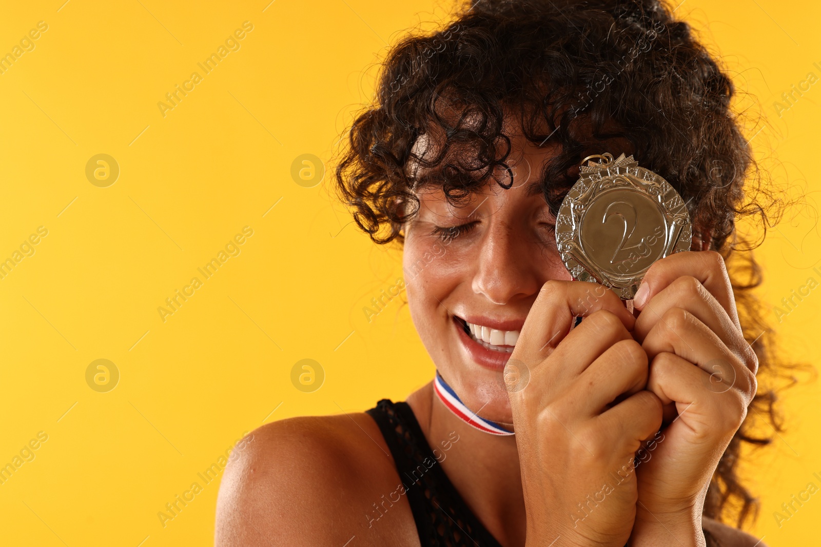 Photo of Happy winner with silver medal on yellow background, closeup. Space for text